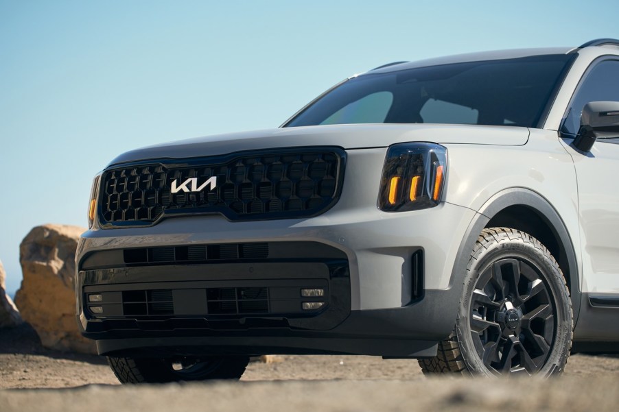 A matte gray 2024 Kia Telluride parked in left front angle view front end and part of left door