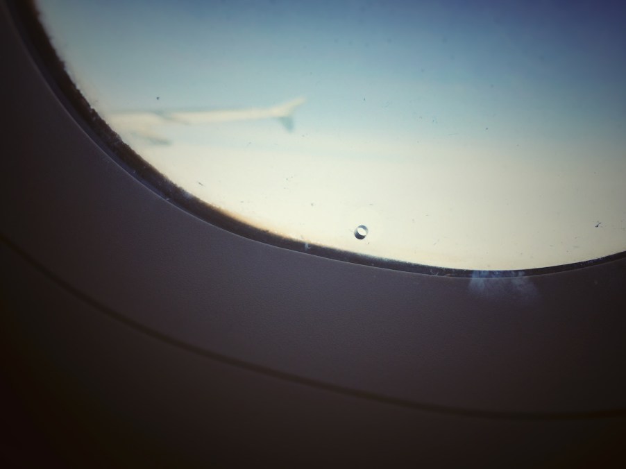 Closeup of the "bleed hole" in the inner layer of a commercial airplane's window.