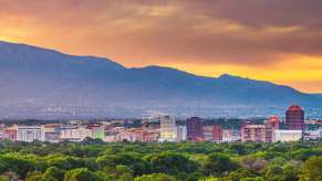 The sunset above the skyline of Albuquerque New Mexico, a green park in the foreground.