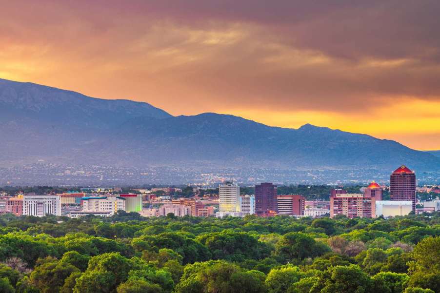 The sunset above the skyline of Albuquerque New Mexico, a green park in the foreground.