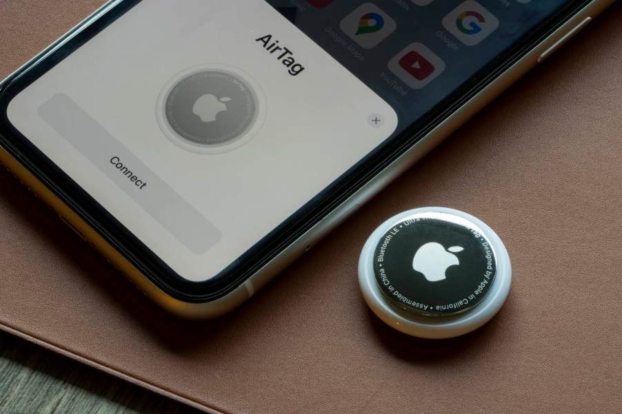 An Apple Airtag GPS tracker sitting next to an iPhone