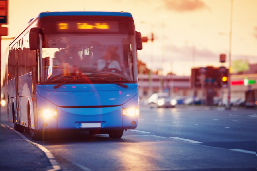 Blue city bus in front of the sunset.