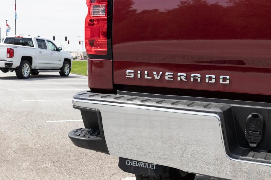 The Silverado badge on the tailgate of a red Silverado pickup truck.