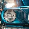 An owner works on an old, classic car in their shop.