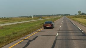 A camera vehicle following a police officer in a state trooper Dodge Charger on the highway.