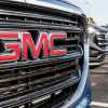 The red "GMC" letters in the chrome grille of a pickup.