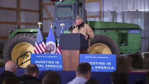 Governor Tim Walz stands in front of a John Deere tractor at President Joe Biden's Investing in Rural America tour