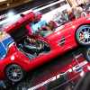 Red Mercedes gullwing SLS coupe at an auto show.