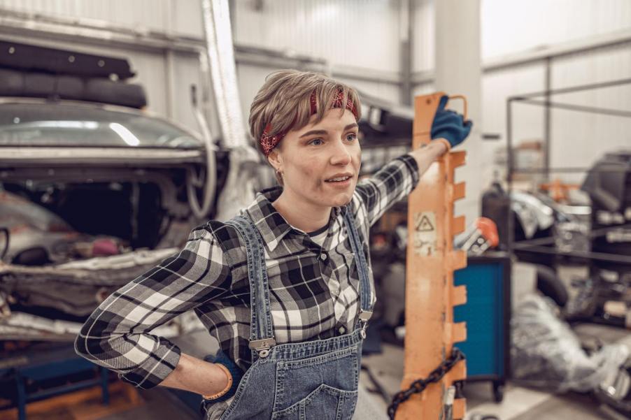 Young Millennnial or Gen Z mechanic DIYer stands in a garage auto shop.