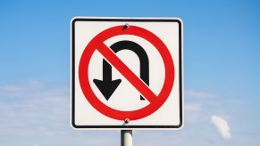 White and red "no U-turn" sign against a blue sky.