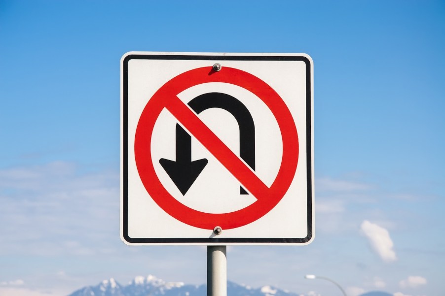 White and red "no U-turn" sign against a blue sky.