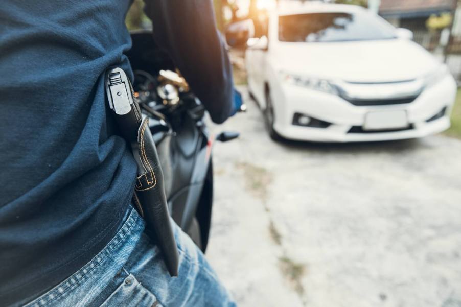 A motorcycle rider hits the road with an open carry handgun on his hip.