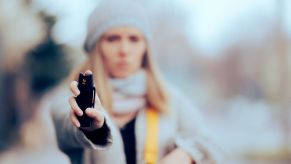 A woman with OC spray points it at an attacker.