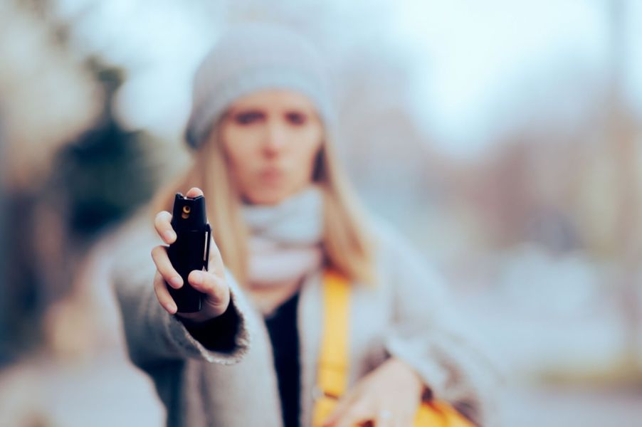 A woman with OC spray points it at an attacker.