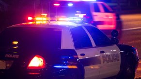 Police officers driving a Ford Crown Victoria prepare to deploy spike strips to stop a chase.