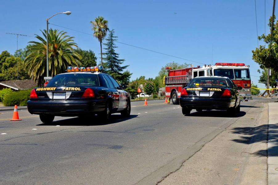 Police officers pull over with a fire truck at an emergency scene.