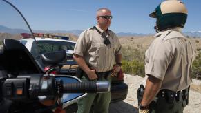 Two police officers stand by the road side and talk.