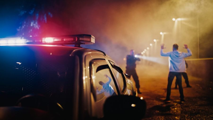 Police pull over a man and draw their weapons on him at night.