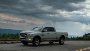 Heavy-duty Ram pickup truck with a Cummins engine parked on a mountain road, dark clouds visible in the background.