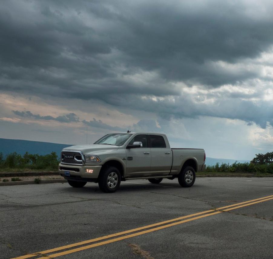 Heavy-duty Ram pickup truck with a Cummins engine parked on a mountain road, dark clouds visible in the background.