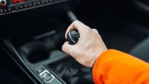 A driver's hand as they shift into reverse.