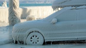 SUV parked by a lake and coated in ice by the wind.