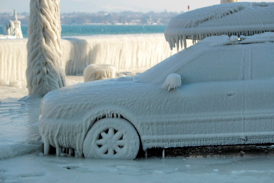 SUV parked by a lake and coated in ice by the wind.