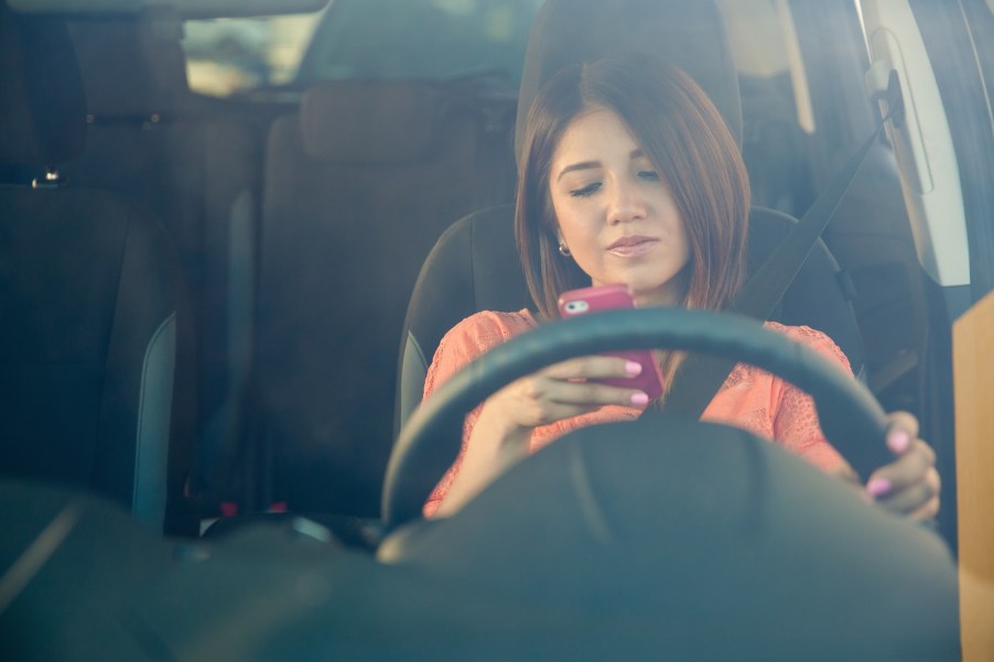 Woman texting while driving her car.