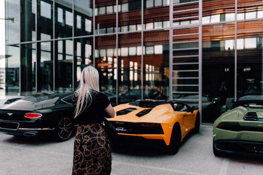 Woman listens to exotic cars at a car show.