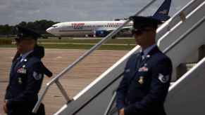 A view of Trump and Vance campaign plane as it taxis on Wisconsin tarmac with Air Force Two stairs and Secret Service agents in blurred foreground