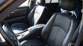 A black leather car interior from left front door view sitting in a car for too long can cause back pain