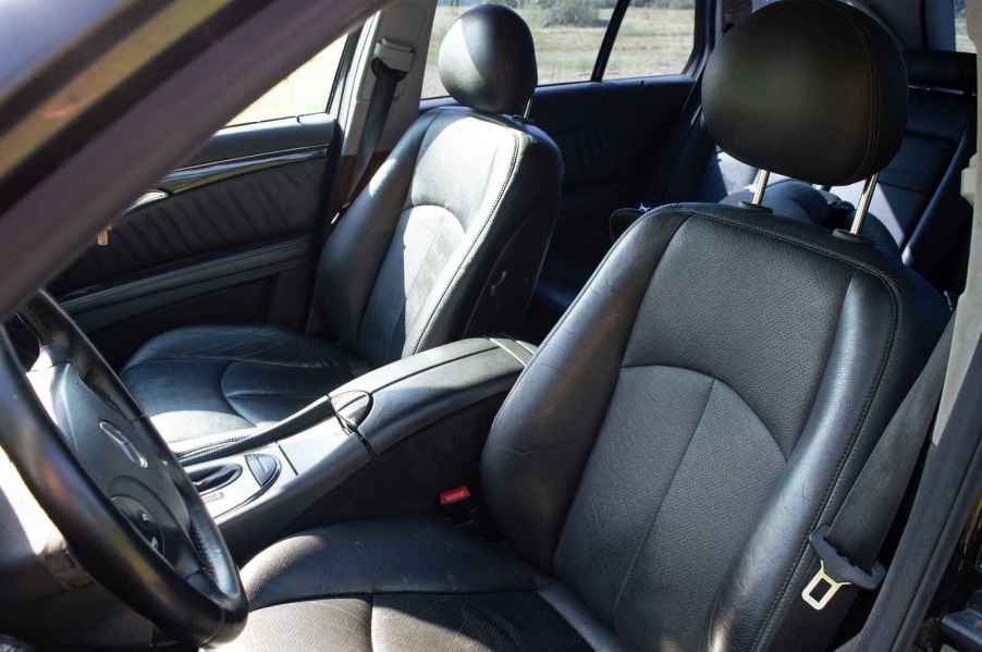 A black leather car interior from left front door view sitting in a car for too long can cause back pain