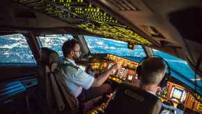 A pilot and co-pilot sitting in the flight deck of a commercial plane such as a Boeing 787