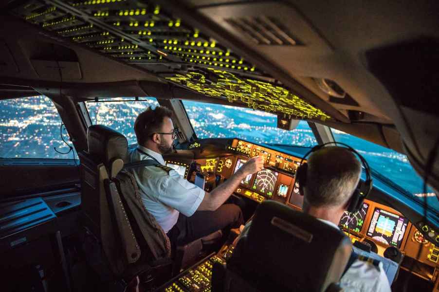 A pilot and co-pilot sitting in the flight deck of a commercial plane such as a Boeing 787