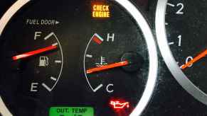 A check engine, brake, oil, and battery dash light inside a car in very close view