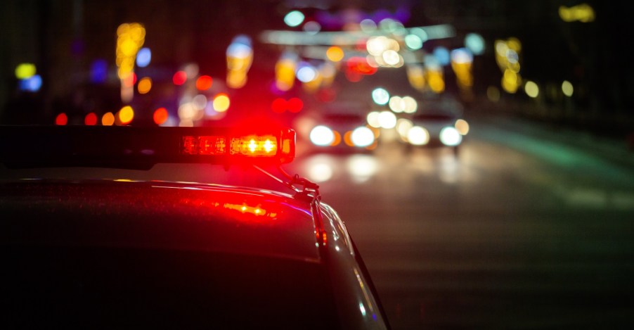 Representation of a DUI checkpoint at night police car roof light in close view blurred cars in background