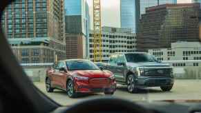 Two Ford EV models, F-150 Lightning and Mustang Mach-E, parked on a city building rooftop in right front view