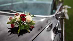 Depiction of a black funeral procession car with flowers on the hood in close view