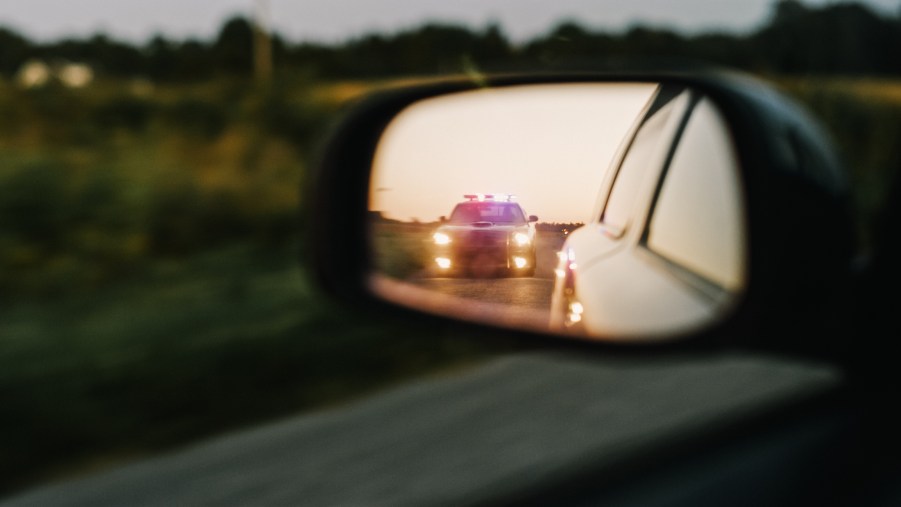 View of a police cruiser in the side mirror of a car.