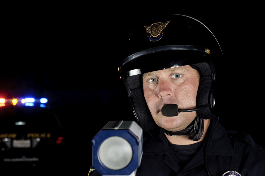 A police officer near his car with a radar gun