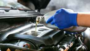 Automotive tech at Quick Lube facility wearing blue gloves fills car with oil in very close view