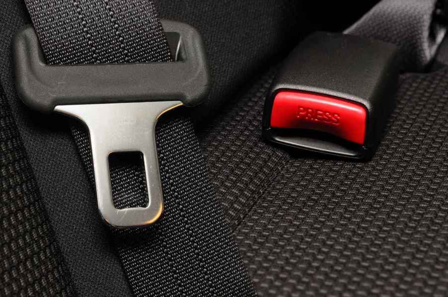 A back car seat belt, latch, and buckle in close view on black fabric seat