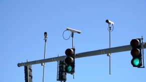 Three traffic light cameras against a blue sky