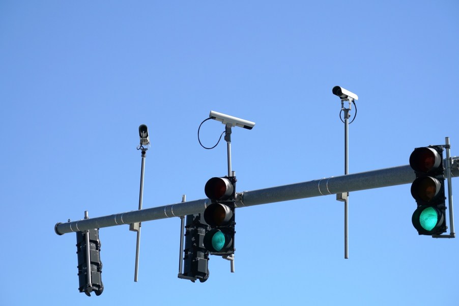 Three traffic light cameras against a blue sky