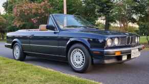 A black 1990 BMW 325i E30 convertible parked with the top down in right front angle view