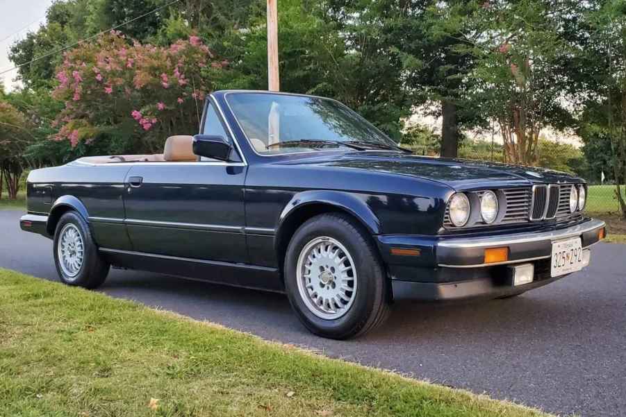 A black 1990 BMW 325i E30 convertible parked with the top down in right front angle view