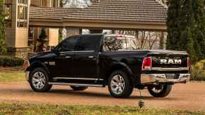 A black 2015 Dodge Ram 1500 parked in left rear angle view in front of a house