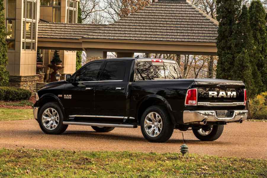 A black 2015 Dodge Ram 1500 parked in left rear angle view in front of a house