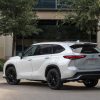 A pearl white 2023 Toyota Highlander parked outside in left rear angle view