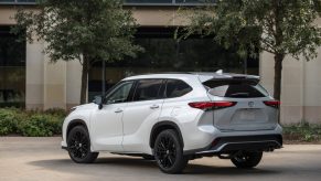 A pearl white 2023 Toyota Highlander parked outside in left rear angle view